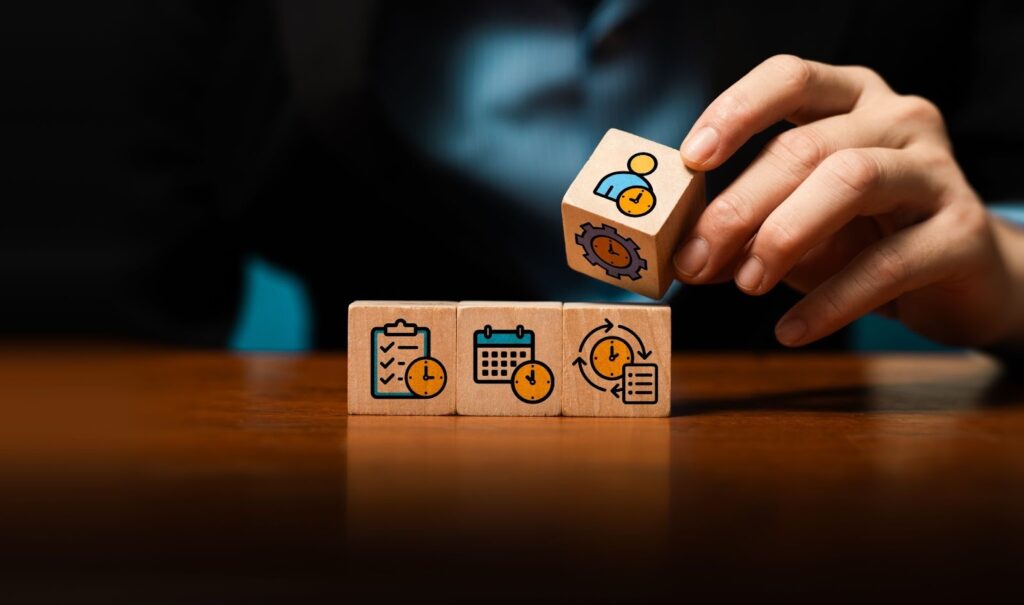 A person in a business suit places a wooden block atop a row of three others.