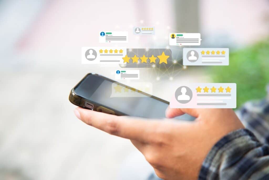 A person's hand holding a smartphone with several digital user review bubbles floating above the screen.