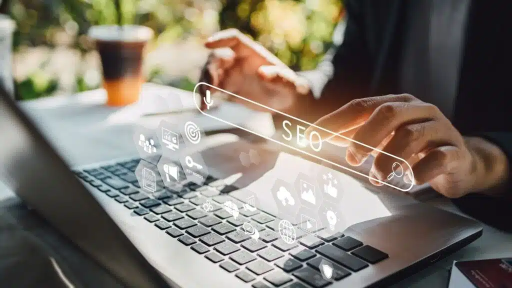 A person's hands using a laptop with a digital holographic search bar displaying the text "SEO"