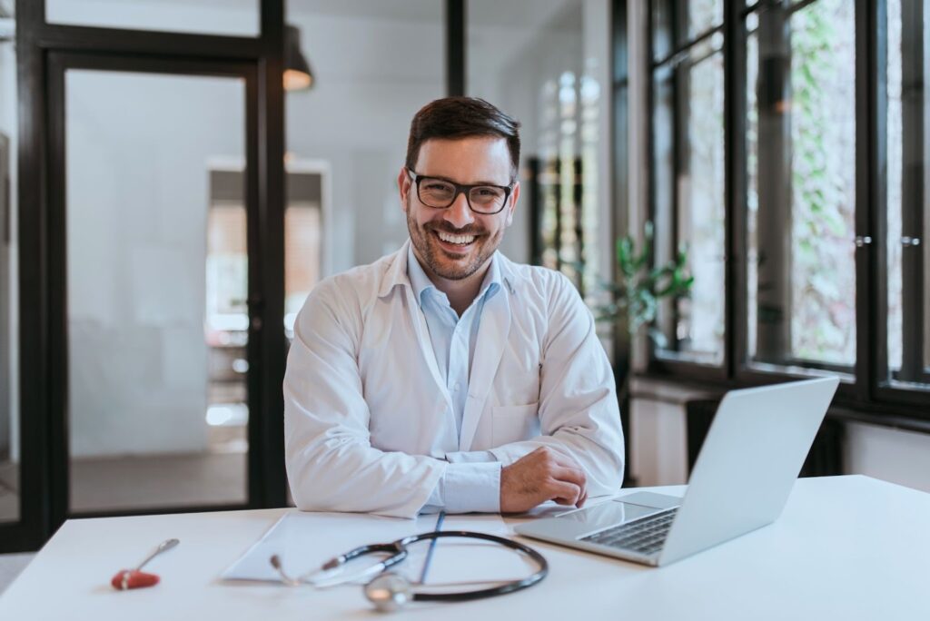 Portrait of a smiling doctor sitting at a desk in the office.