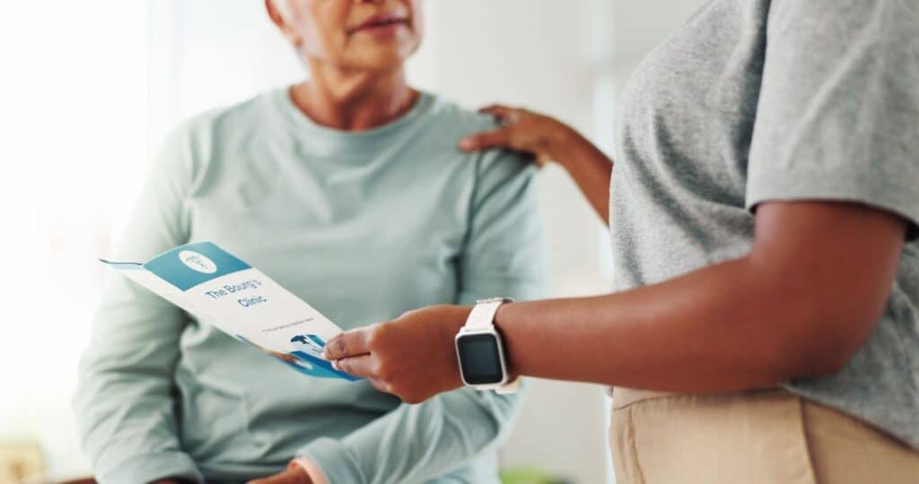 A patient and a doctor with a brochure for PT care.