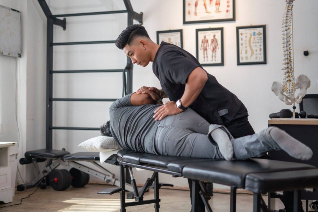 Chiropractor performing a Chiropractic adjustment on a patient lying on a treatment table.