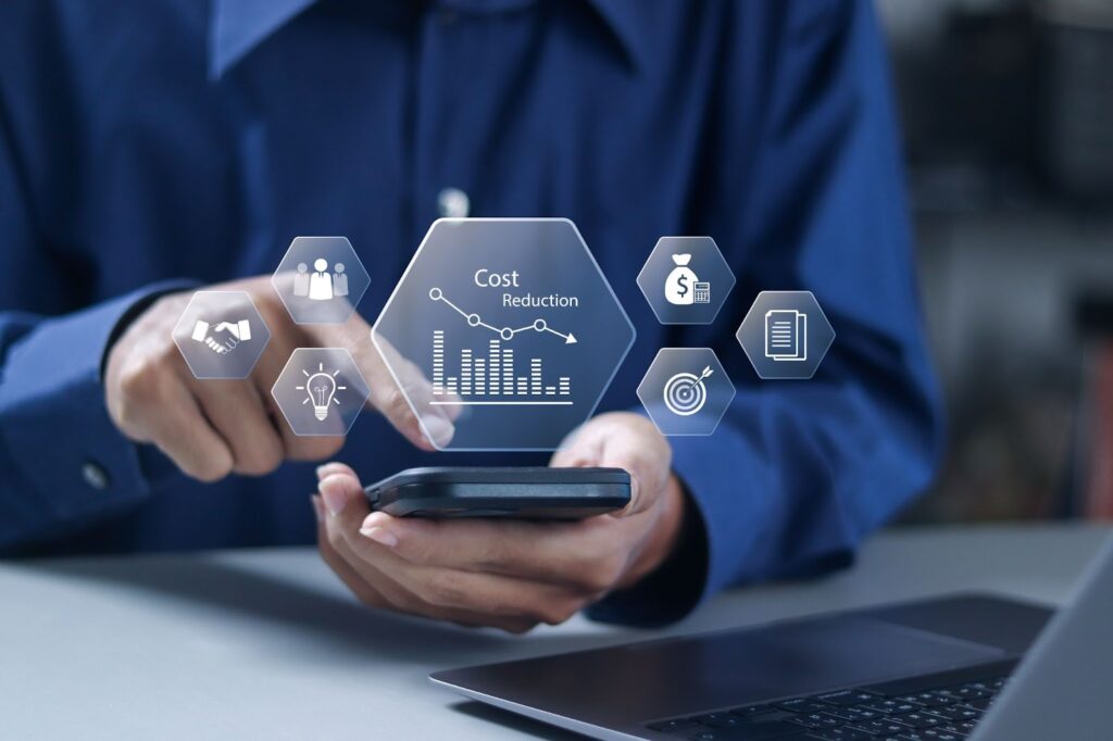 A person in a blue shirt uses a smartphone with a digital "Cost Reduction" interface floating above it.