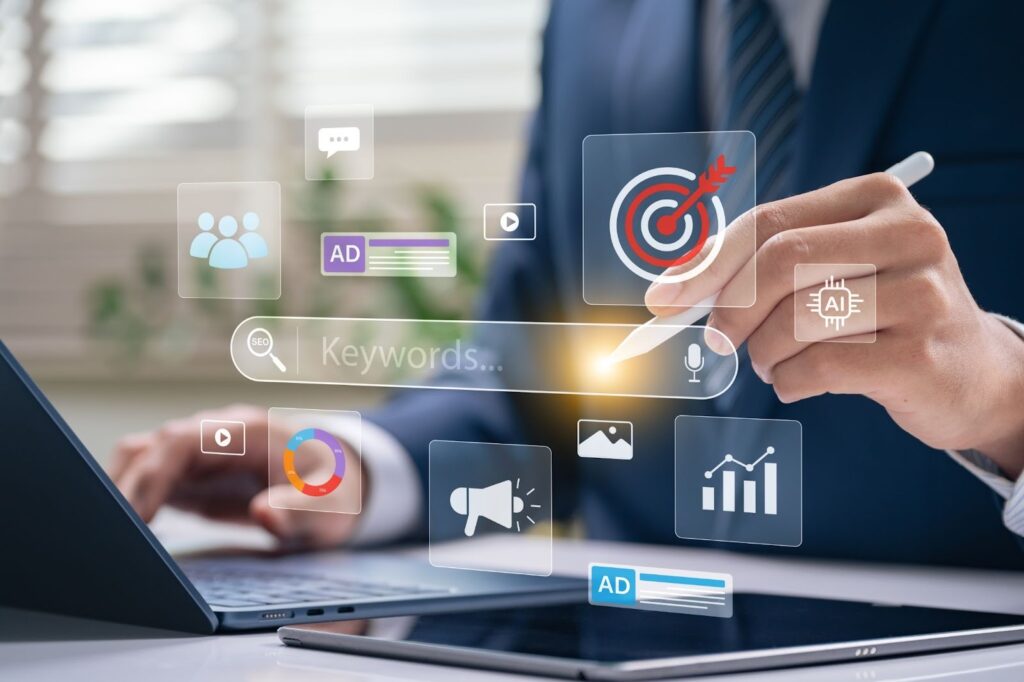 A person in a business suit using a stylus on a tablet and a laptop, with digital icons floating in the air representing search engine optimization and digital marketing.