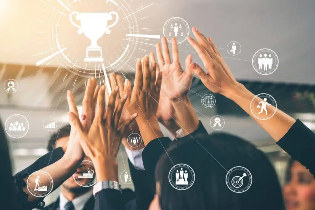 A diverse team of healthcare professionals raising their hands in a celebratory huddle.