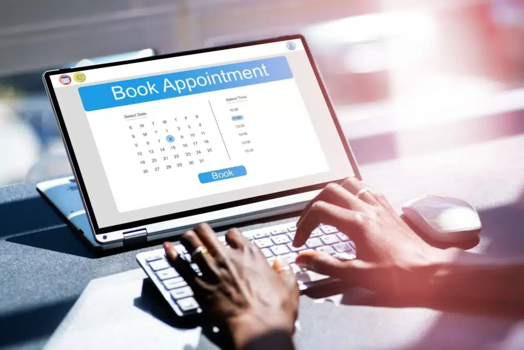 An over-the-shoulder view of a person using a laptop to book an appointment through an online interface.
