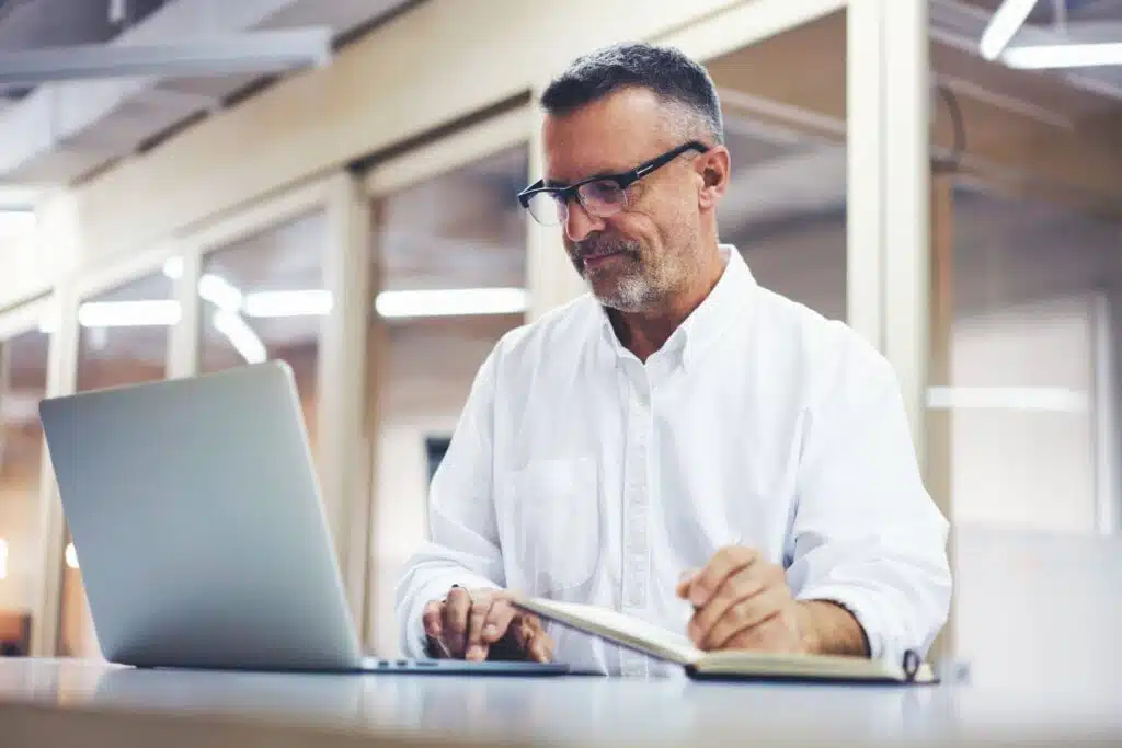 A man with glasses and a white shirt booking his online PT appointment.